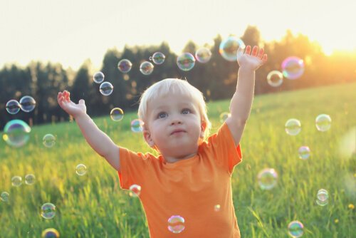 A boy playing with soap bubbles in a field.