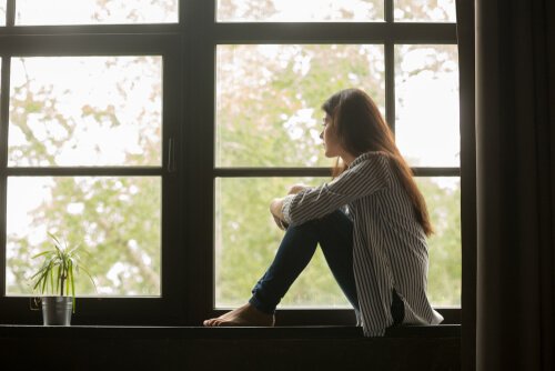 A sad woman looking out the window and contemplating her life.