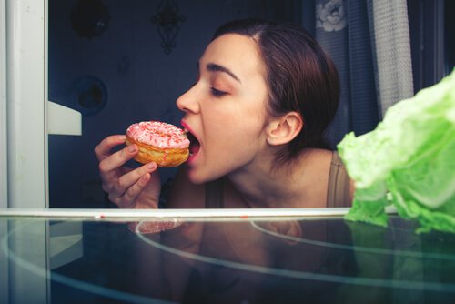 A woman eating a donut at night.