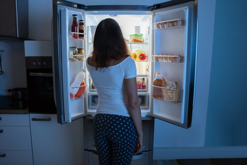 A woman looking at her fridge.