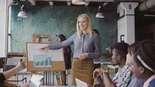 A woman doing a presentation for a small group of people in a spacious building.