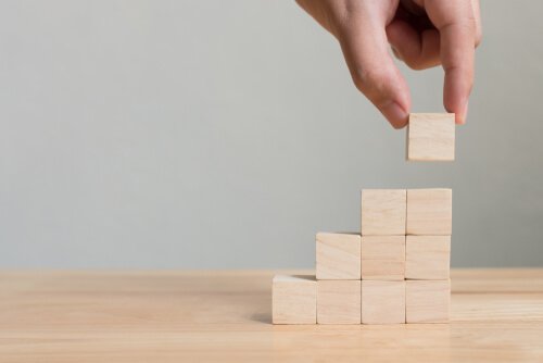 A hand placing wooden cubes on top of each other making a tower.