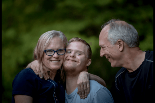Two older adults and a young man with Down syndrome.