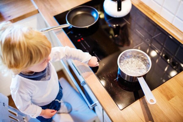 A baby playing around, touching a stovetop with hot things on it.