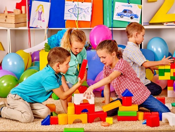 A group of children playing with large, colorful building blocks.