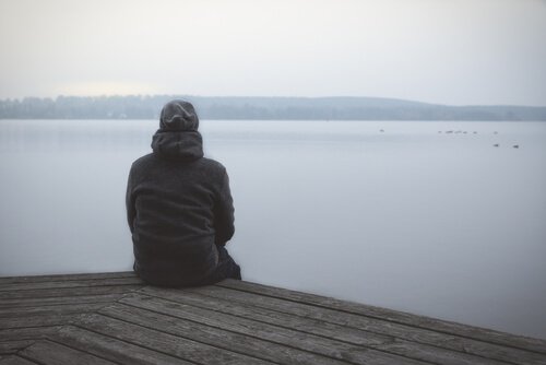 A guy looking out at a wintry lake.