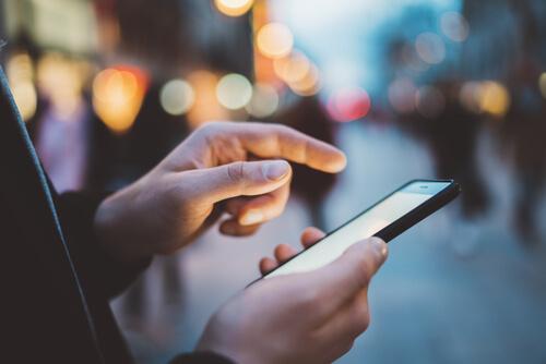 A close-up showing someone using their smartphone in the street.
