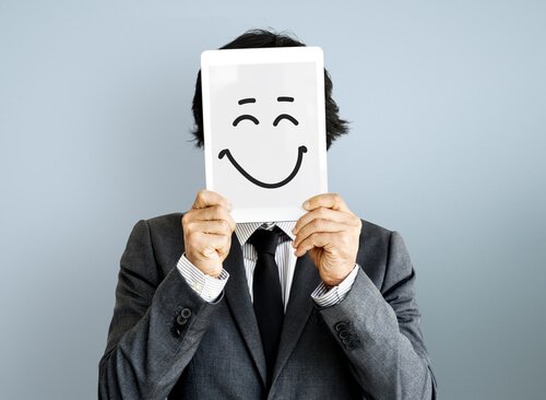 A man holding a happy face drawn on a paper.