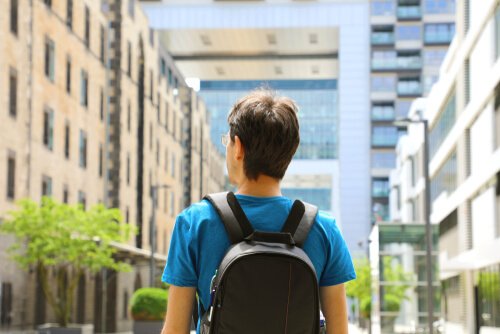 A man wearing a backpack, looking out onto a city street.