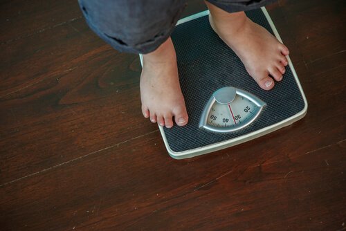 An obese man weighing himself.
