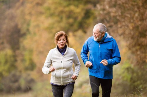 Two older people jogging together.