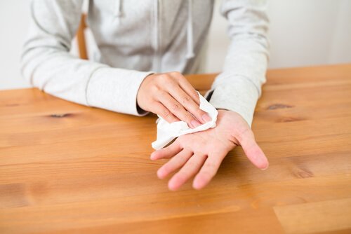 A person wiping their sweaty hand with a napkin.