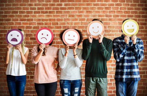 People with drawn masks of different emotions.