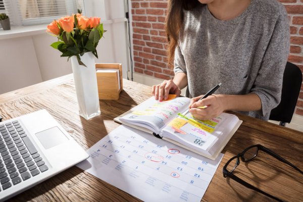 A woman sitting at a desk and highlighting things in a textbook.