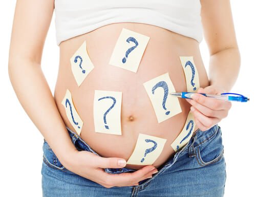 A pregnant woman with question marks on her belly.