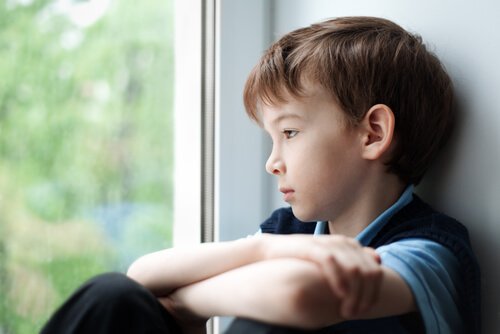 A sad little boy looking out the window.