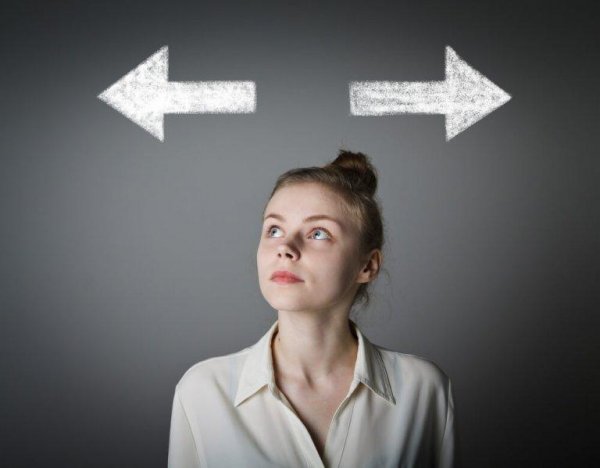 A woman looking up at two arrows as she tries to decide which way to go, symbolizing rational choice theory.