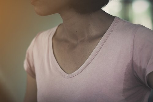 A picture showing a woman in a shirt with large sweat armpit stains.