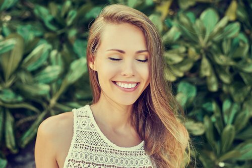 Woman smiling with eyes closes while outdoors.