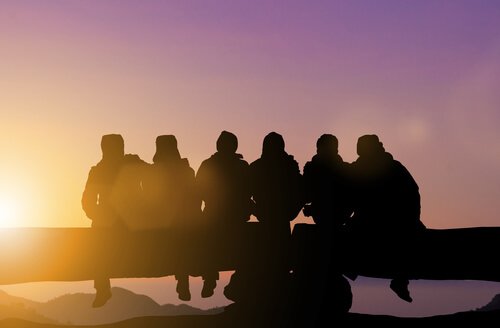 A group of friends seated on a rail.