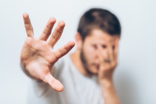 A seemingly upset man telling someone to go away with his hand.