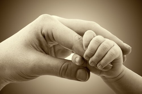 A baby holding an adult's hand.