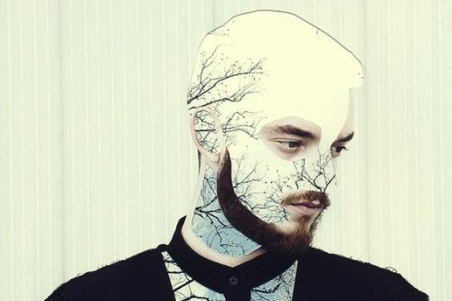 man with his face changed with paper cutouts of white scenery and trees