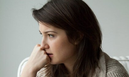 A woman with her hand on her chin. looking worried.