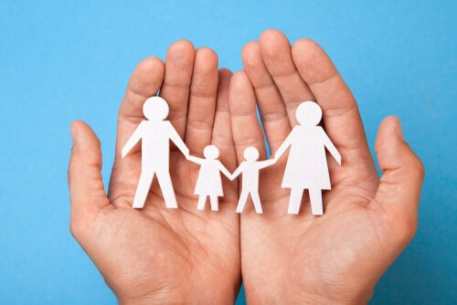hands holding a paper cutout of a family