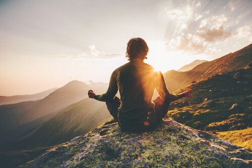 a man meditating on top of a mountain, representing the effects of religion on the brain
