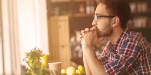 a man with glasses thinking, looking out the window