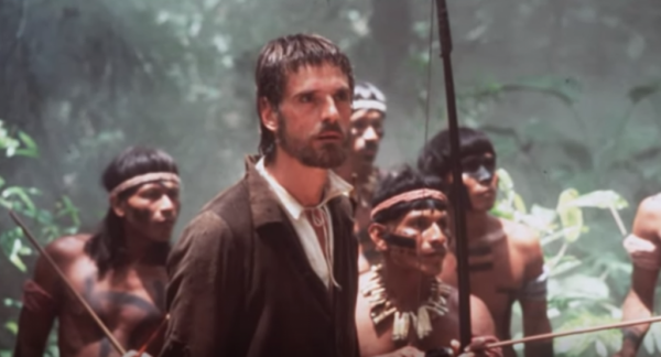 A still from the movie showing Jeremy Irons with a group of native people behind him.