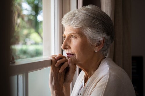 An older woman staring out of a window.