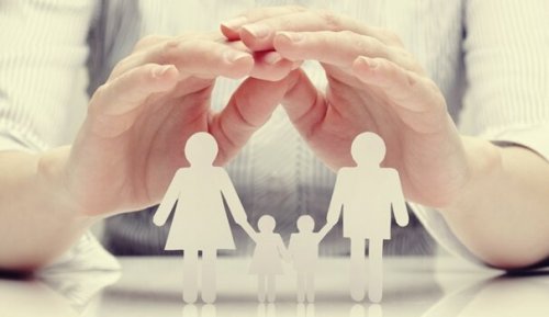 a pair of hands over a paper cut out family