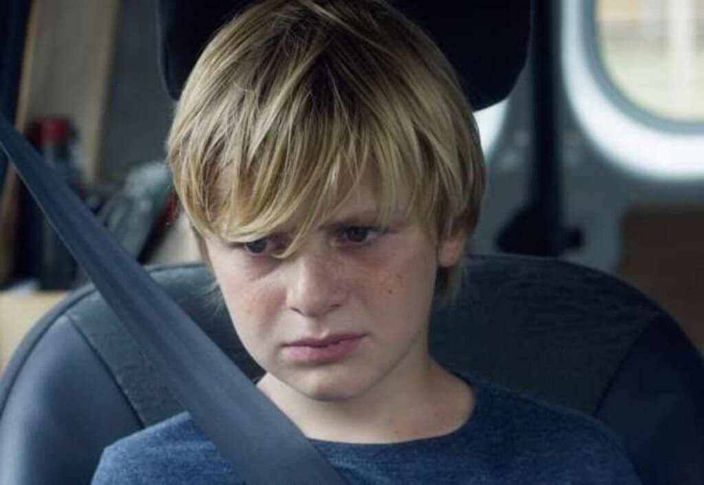 A sad boy in a car.