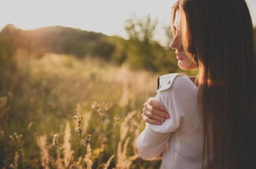 A woman letting her light shine bright as she hugs herself.