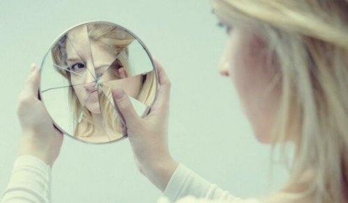 A woman looking at herself in a broken mirror.