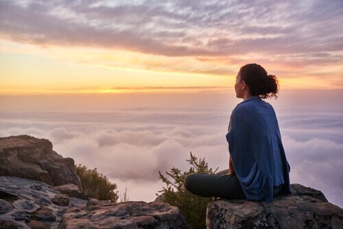 a woman sitting on top of a mountain practicing the concept of value your effort
