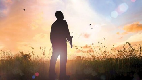A man standing in a field during sunset.