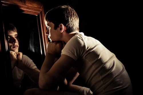 A young man looking at his reflection in the mirror.