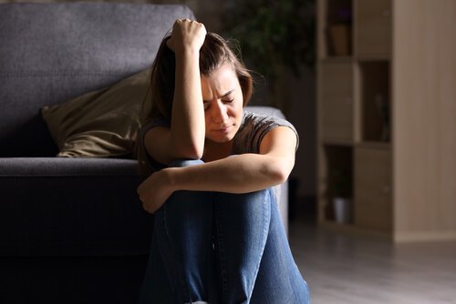 A sad woman sitting on the floor.