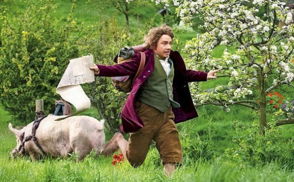 A still image from the movie showing Bilbo Baggins (played by Martin Freeman) running through a field with papers in his hand.