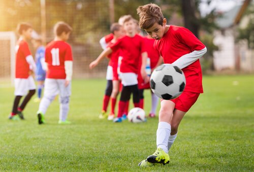 A boy in a youth soccer team kicking a ball.