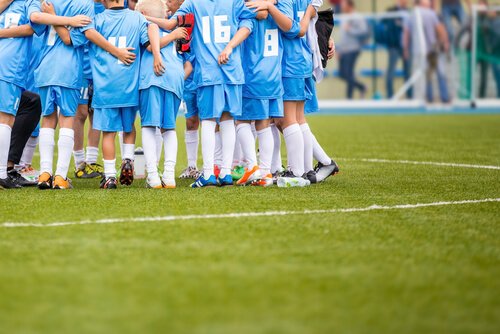 A youth soccer team hudling together.