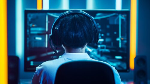 A boy with headphones on playing eSports.