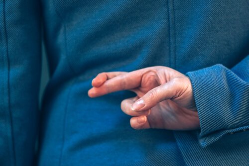 A person crossing their fingers behind their back.