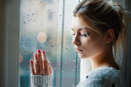 A sad woman with her hand on the window.