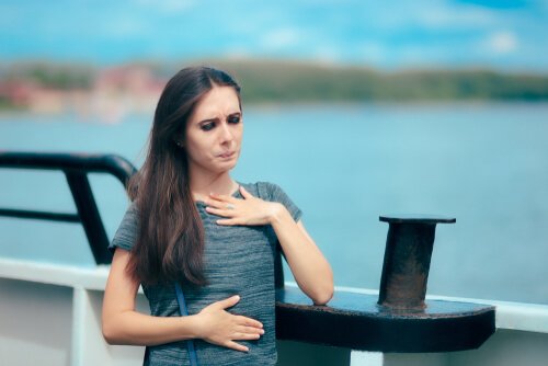 a woman with aquaphobia, or the fear of water, that is feeling nausea as she stands near the edge of a boat