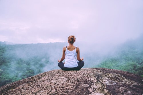 A woman meditating on a mountaintop.