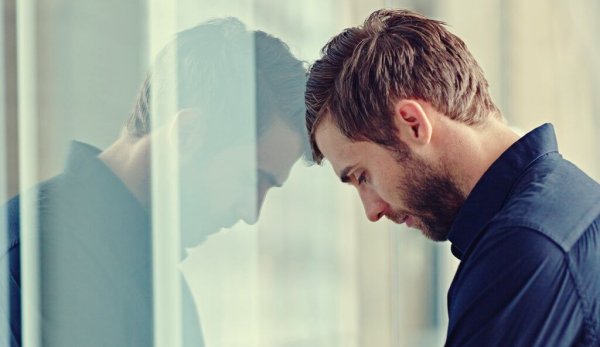 A man with his head against a window.
